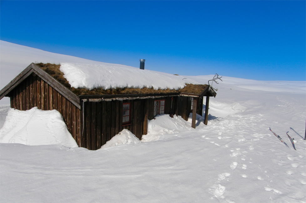 en hytte på fjellet om vinteren og blå himmel